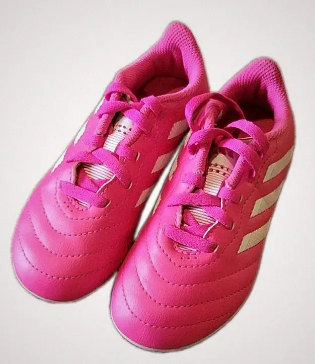 These are vibrant pink Adidas youth soccer cleats featuring classic white...